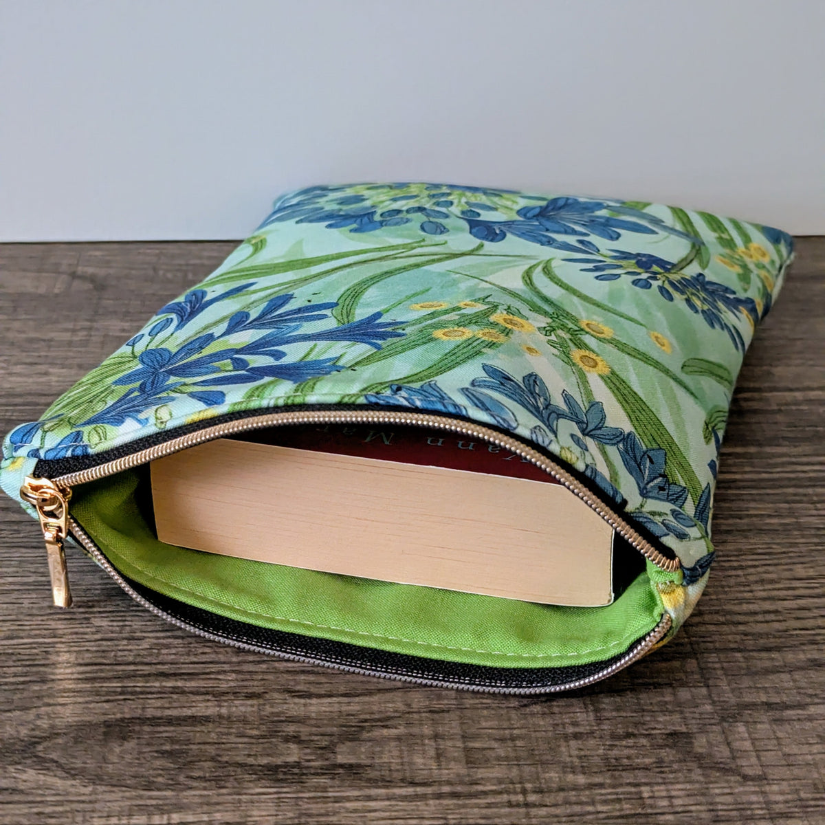 Floral-patterned pouch with a book inside on a wooden surface