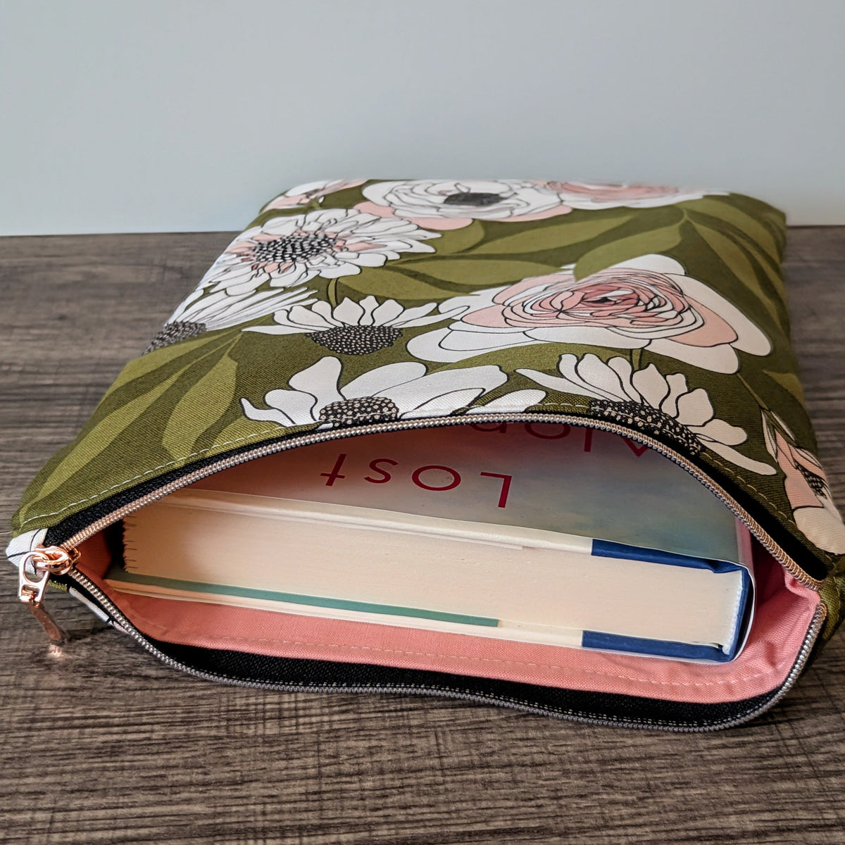Floral-patterned pouch with books inside on a wooden surface