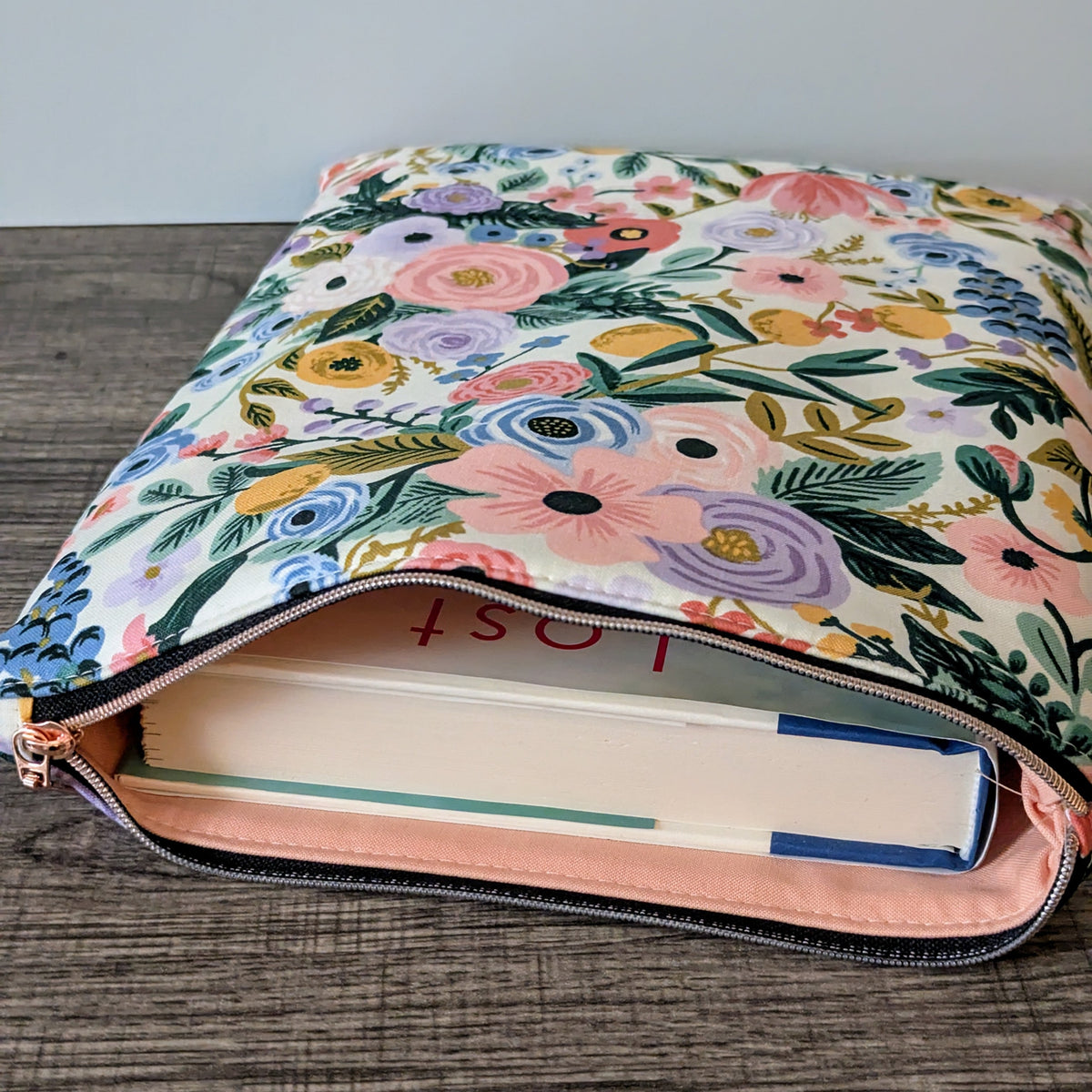Floral-patterned pouch with a book inside on a wooden surface