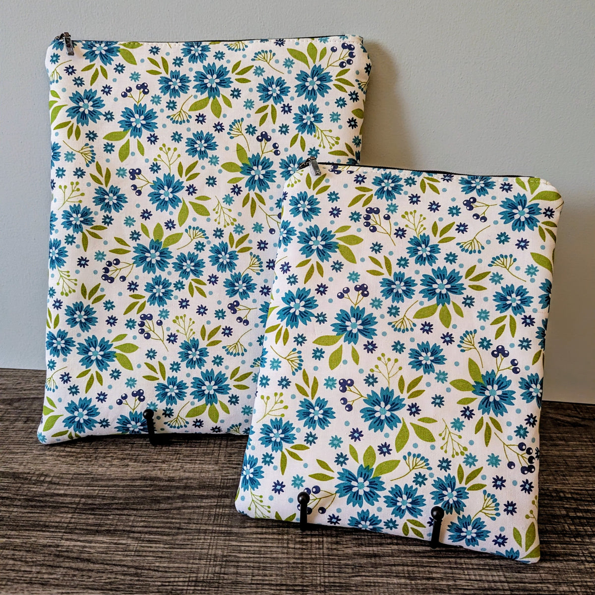 Two floral-patterned bags on a wooden surface with a neutral background