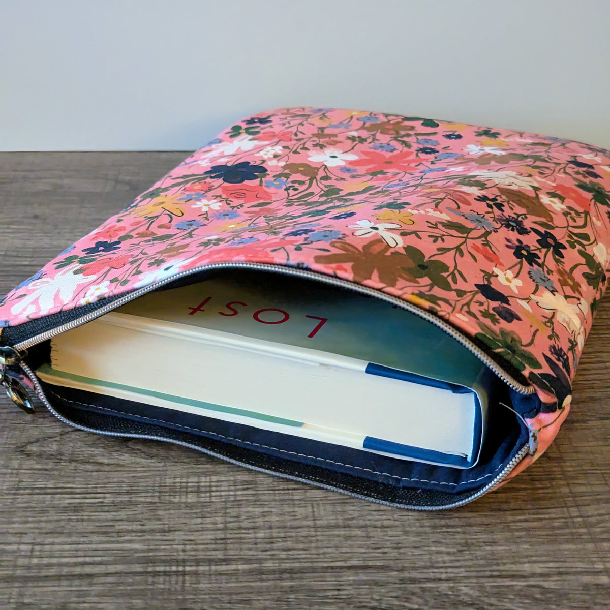 Floral-patterned pouch with a book inside on a wooden surface