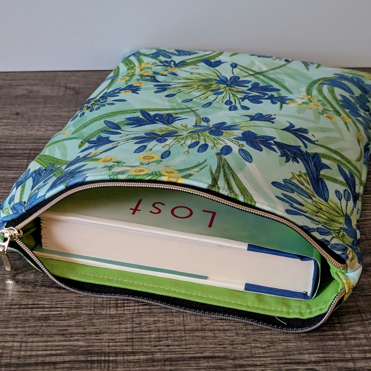 Floral-patterned pouch with a book titled 'Lost' on a wooden surface