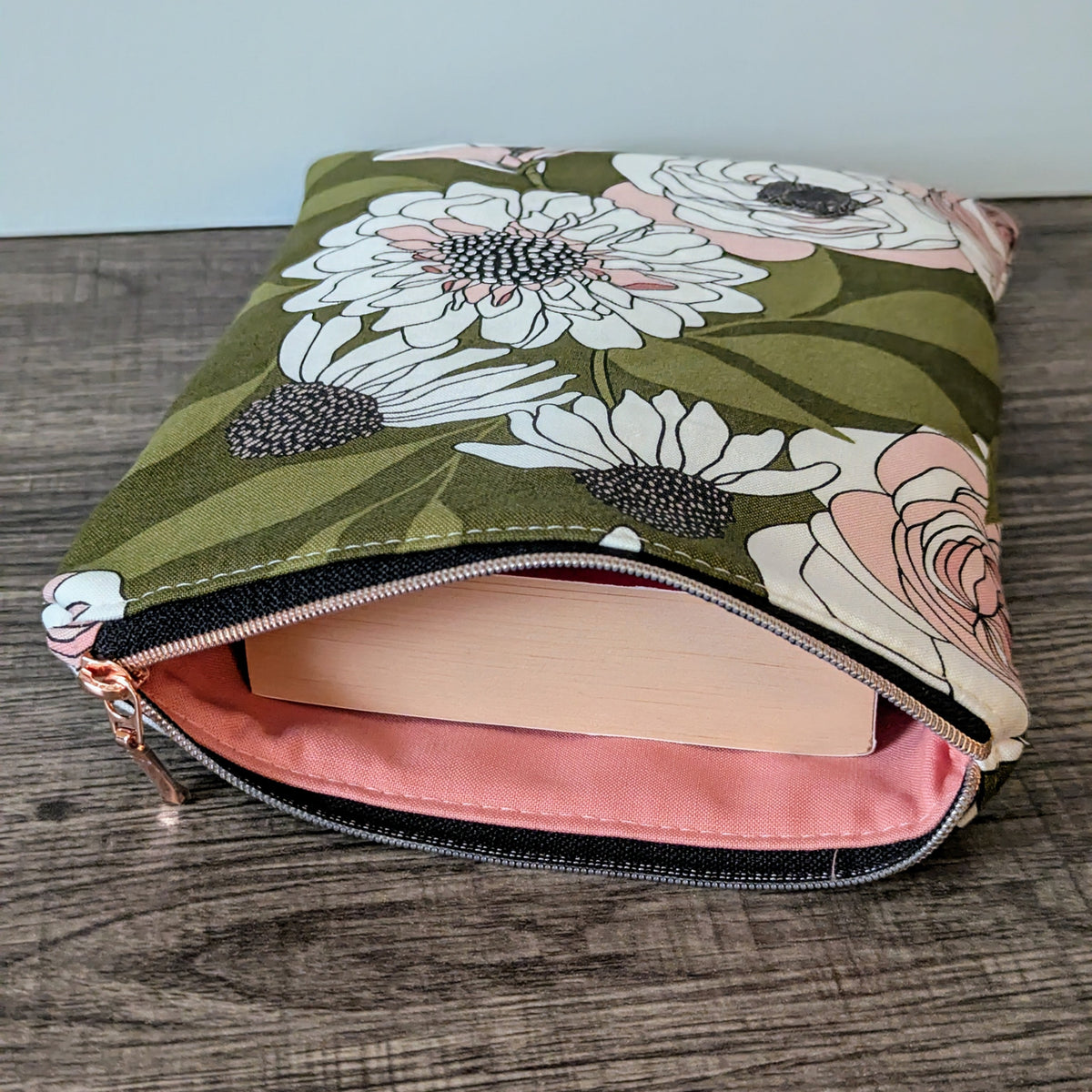 Floral-patterned pouch with pink interior on a wooden surface