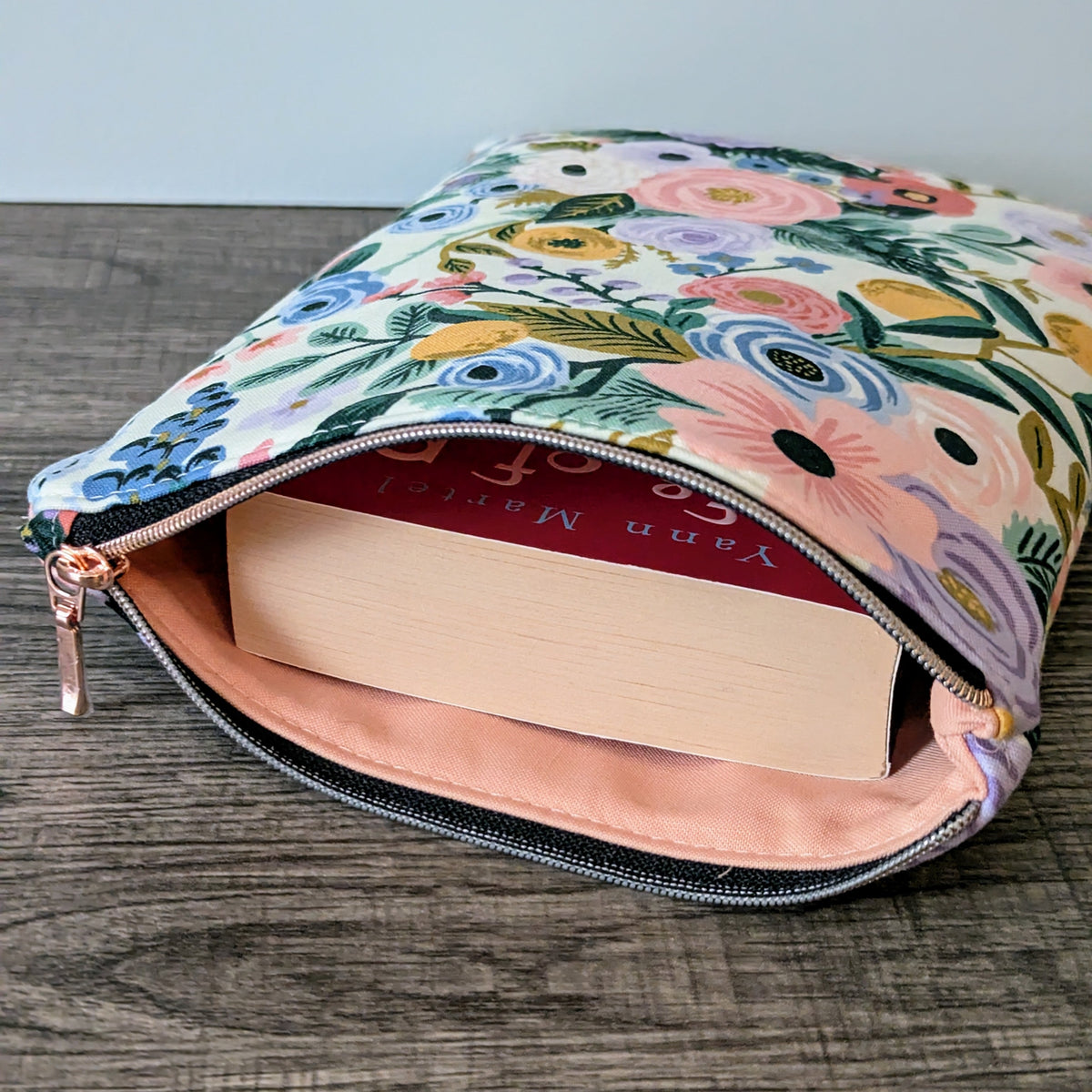 Floral-patterned pouch with a book inside on a wooden surface