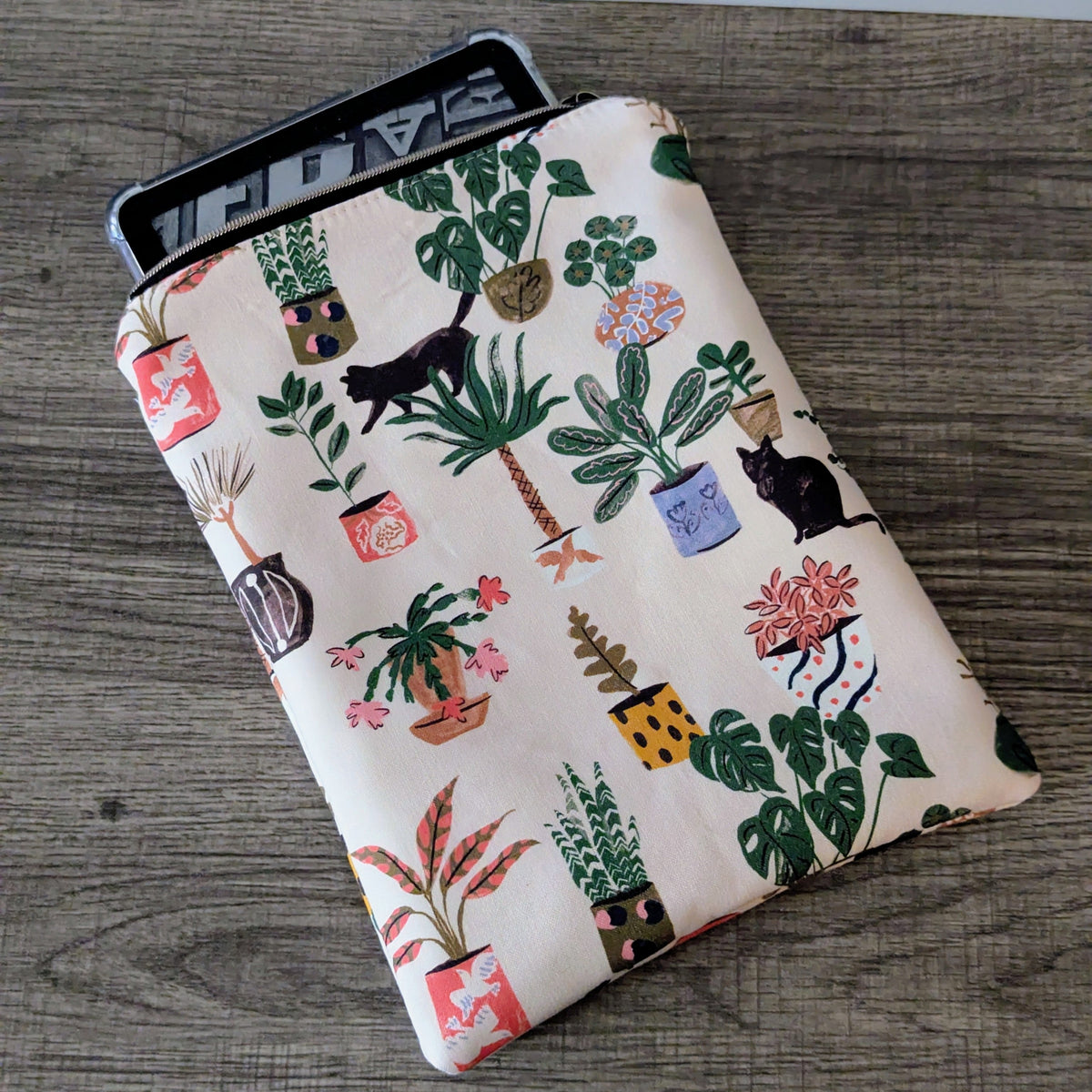 Tablet case with plant and cat pattern on a wooden surface