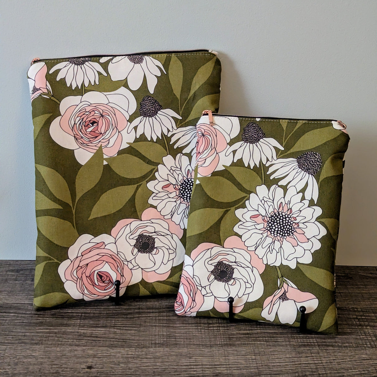 Two floral pouches with pink and white flowers on a green background, placed on a wooden surface.