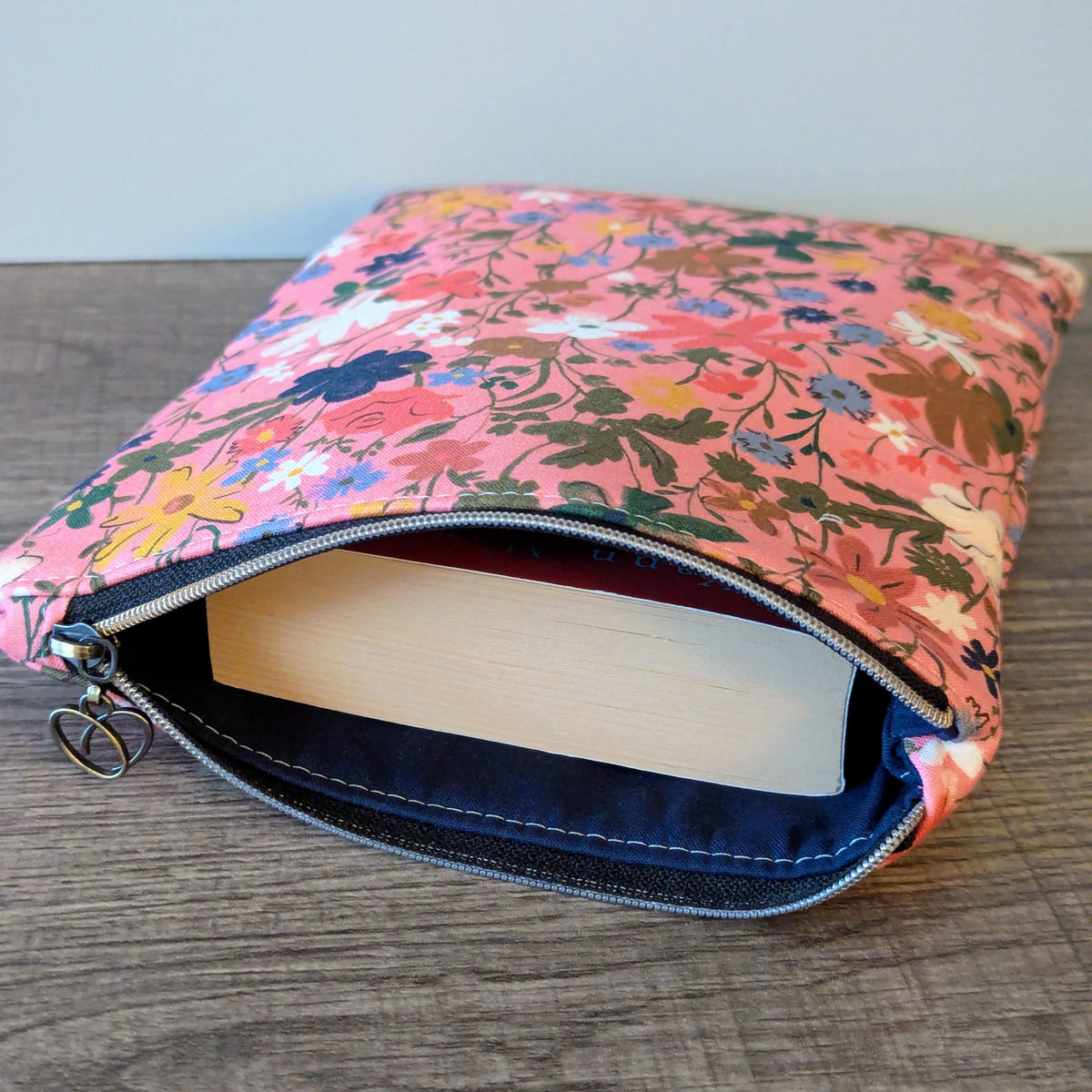 Floral-patterned pouch with a book inside on a wooden surface